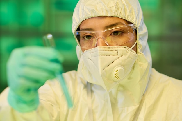 Wissenschaftlerin in Schutzbrillen-Atemschutzmaske und Biogefährdungsanzug