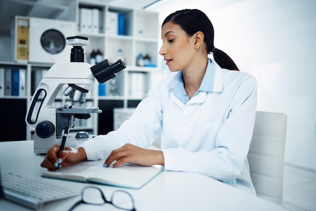 Wissenschaftlerin schreibt Notizen in der Forschung für wissenschaftliche Durchbrüche oder Informationen im Labor. Weibliche Person oder medizinische Expertin mit Notizbuch für wissenschaftliche Daten oder Ergebnisse im Labor