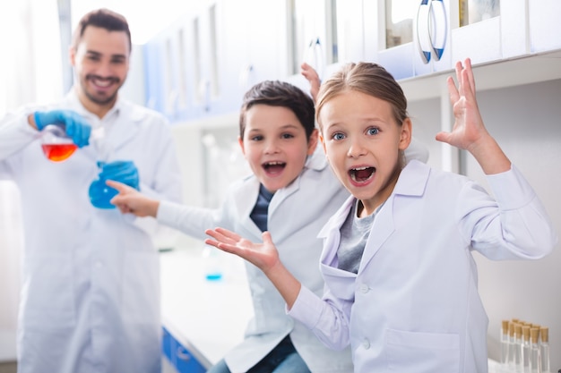 Wissenschaftliche Studie. Glückliche positive nette nette Kinder, die im Labor sind und sich aufgeregt fühlen, während sie das Experiment beobachten