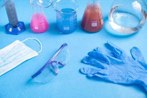 Wissenschaftsglas mit farbigen flüssigen Handschuhen und Gläsern.