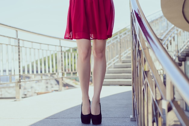Wmans Beine in High Heels und rotem Kleid auf der Treppe