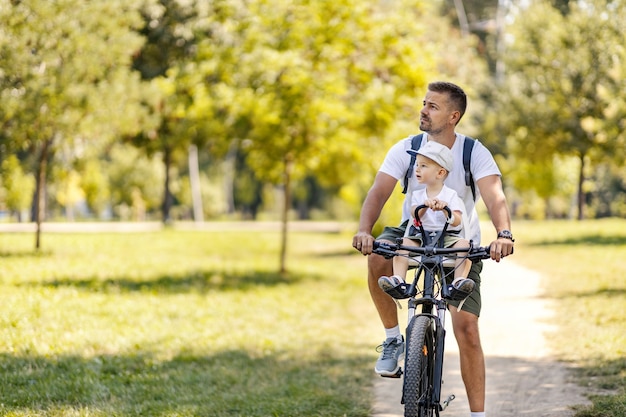 Porträt Eines Kleinen Jungen, Der Auf Einem Abschlepp-Tandem-Fahrrad Fährt,  Das An Den Vater Auf Der Städtischen Straßenansicht Von Vorne Angeschlossen  Ist Lizenzfreie Fotos, Bilder und Stock Fotografie. Image 166722158.