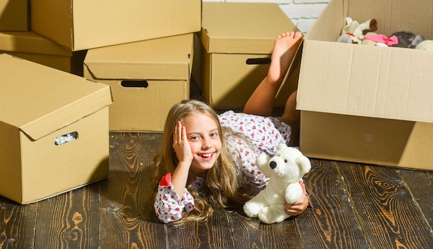 Wochenenden glückliches Kind Karton Kauf einer neuen Wohnung glückliches kleines Mädchen mit Spielzeug spielen in neue Heimat neue Wohnung Kartons Umzug in neues Haus