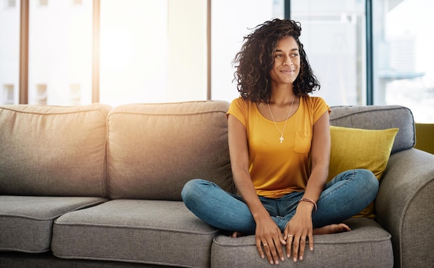 Wochenenden sind wie fürs Sofa gemacht Ganzkörperaufnahme einer attraktiven jungen Frau, die nachdenklich aussieht, während sie sich am Wochenende zu Hause entspannt