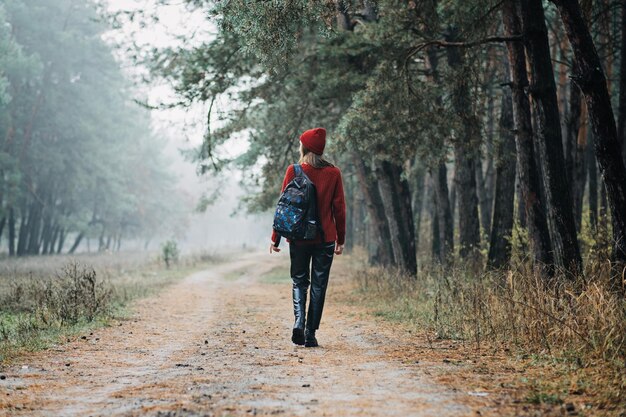 Wochenendreisen und Kurzurlaube in Wäldern bleiben der Natur nahe junge Frau in rotem Hut und Pullover mit