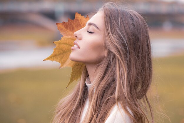 Wodel de moda de mujer de belleza de otoño con hoja de arce de otoño al aire libre