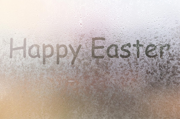 Wörter Frohe Ostern auf einem nebligen Fenster.