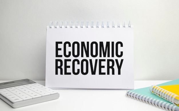 Wörter zur wirtschaftlichen Erholung auf Notizbuch- und Stiftdiagrammen und Taschenrechner