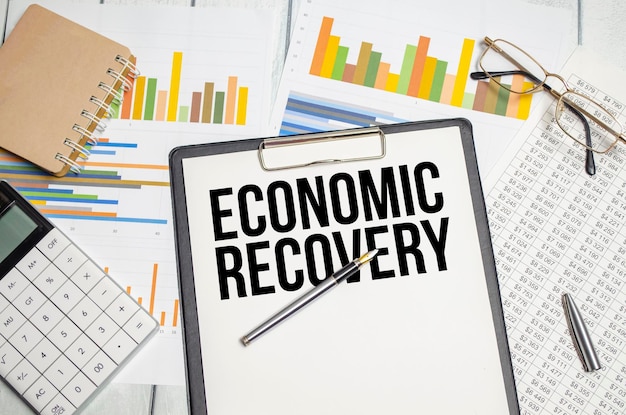 Wörter zur wirtschaftlichen Erholung auf Papiertabletten und Stiftdiagrammen und Taschenrechner