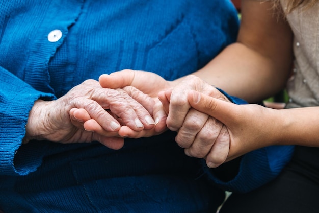 Wohltätigkeitsorganisationen für ältere Menschen Junge Hände halten alte ältere Senioren Hände Unterstützung für das Seniorenkonzept
