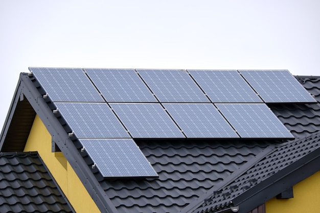 Wohnhaus mit Dach, das mit Solar-Photovoltaik-Paneelen zur Erzeugung sauberer ökologischer elektrischer Energie in einem ländlichen Vorort bedeckt ist Konzept des autonomen Hauses