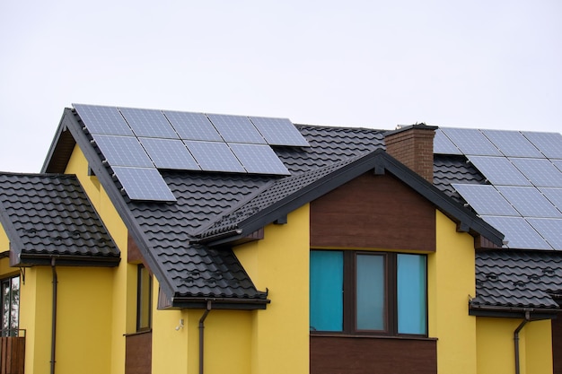 Wohnhaus mit Dach, das mit Solar-Photovoltaik-Paneelen zur Erzeugung sauberer ökologischer elektrischer Energie in einem ländlichen Vorort bedeckt ist Konzept des autonomen Hauses