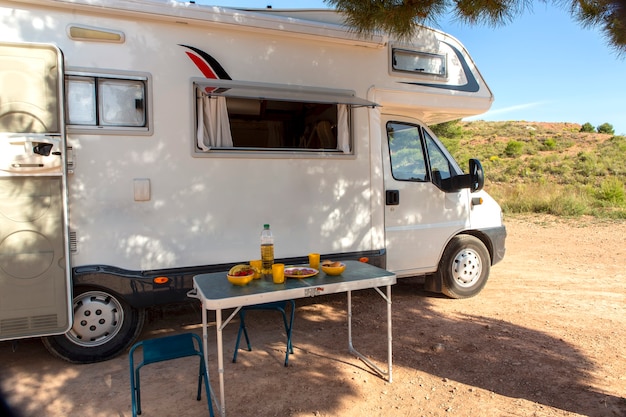 Wohnmobil mit offenem Fenster und einem Tisch mit Essen, Getränken und Obst, um die Ruhe zu genießen