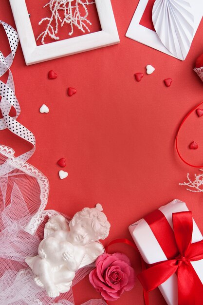 Wohnung lag am Valentinstag mit. Geschenk, Umschlag, Herz und Herzen, Engel, Rahmen und Rose auf rotem Hintergrund