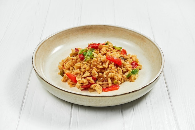 Wok de arroz y verduras en un plato sobre un fondo blanco de madera