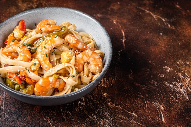 Foto wok chino: fideos udon de marisco salteados con gambas y gambas en un bol