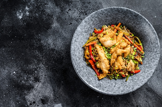 Wok de macarrão de cristal com filé de porco. fundo preto.