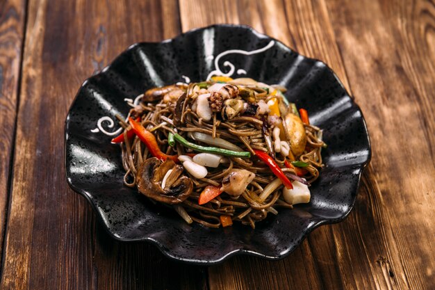 Wok de macarrão soba de frutos do mar em uma placa preta