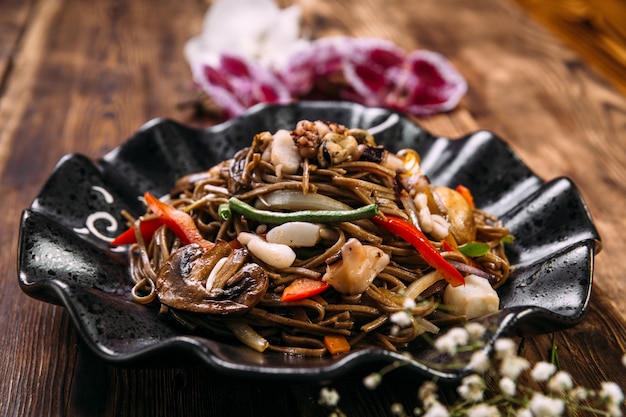 Wok de fideos de soba de mariscos en un plato negro