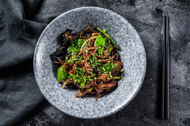 Wok Soba salteado de fideos con carne y verduras. Fondo negro. Vista superior