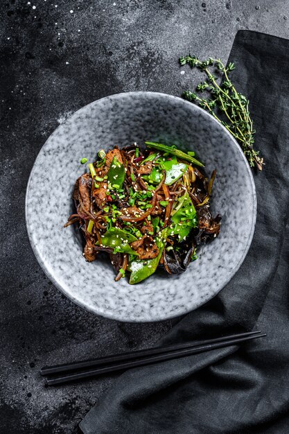 Wok Soba salteado de fideos con carne y verduras. Fondo negro. Vista superior