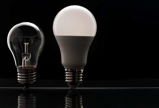 Wolframbirne und LED-Birne auf Schwarz Das Konzept der Stromeinsparung