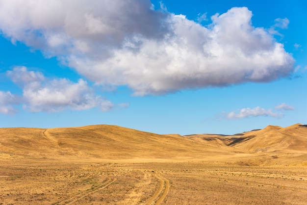 Wolken am blauen Himmel über Bergen mit getrocknetem gelbem Gras