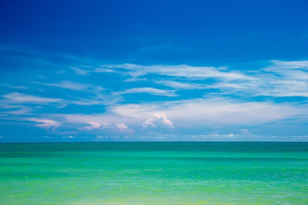 Wolken auf blauem Himmel über ruhigem Meer mit Sonnenlichtreflexion