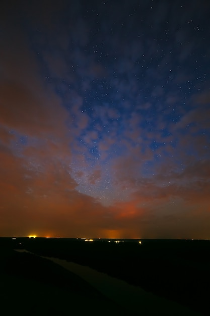 Wolken in der Nacht vor dem Hintergrund heller Sterne am Himmel nach Sonnenuntergang.