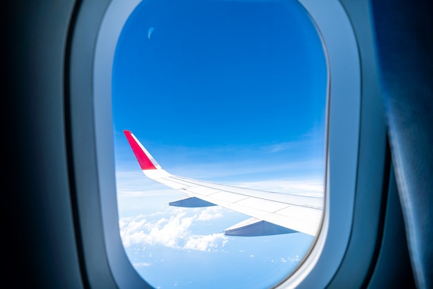 Wolken und Himmel durch das Fenster eines Flugzeugs gesehen