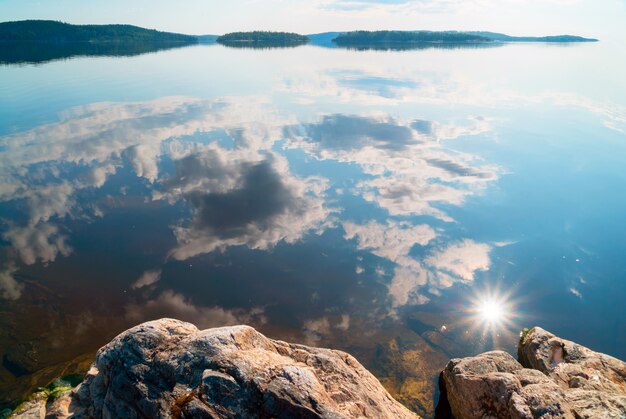 Wolken und sonne mit spiegelbild im wasser auf dem see