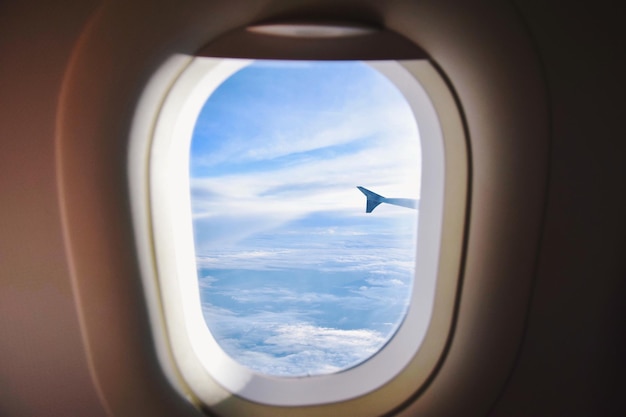 Wolkiger Himmel durch das Flugzeugfenster