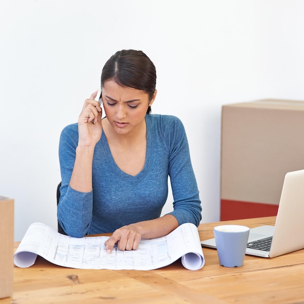 Foto woman phone and call with blueprint for planning communication and scheduling in home office female architect point and concentration with smartphone laptop and paper for project management