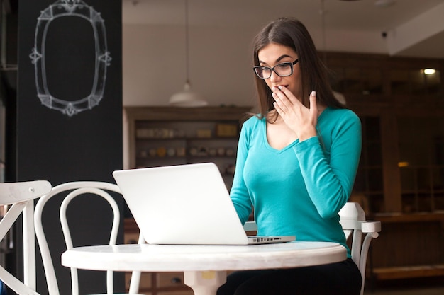 Foto womanfreelancer con gafas negras está trabajando con una computadora portátil en la mesa