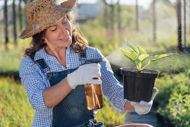 Womangardener está pulverizando uma planta com dispensador de água no jardim