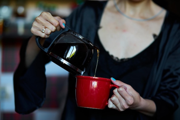 Womans Hand gießt Kaffee hautnah Morgenkonzept