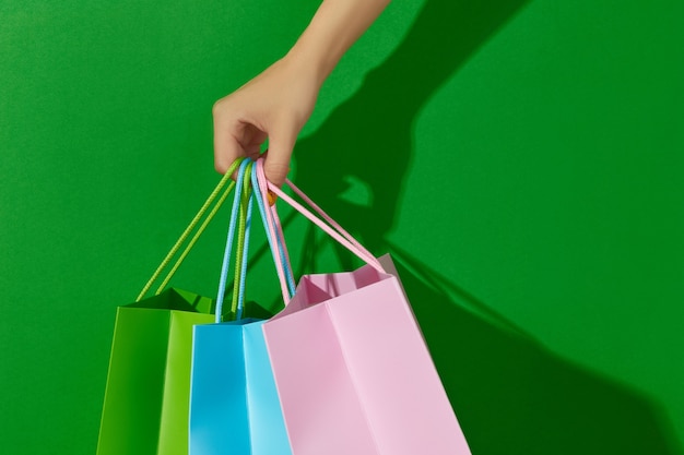 Womans Hand hält Einkaufstüten auf grünem Hintergrund