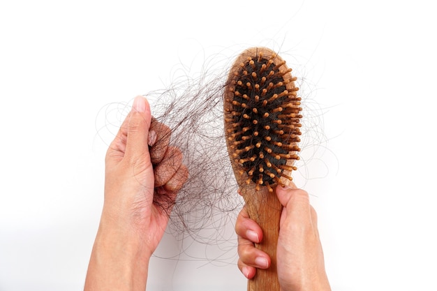 Womans Hand packt die fehlenden Haare auf der Bürste isoliert auf weißem Hintergrund Haare, die gefallen sind