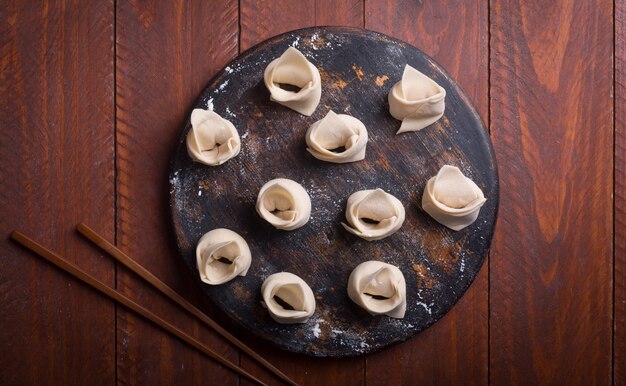 Wonton cru, prato chinês feito de massa e recheios. Fundo de madeira escuro