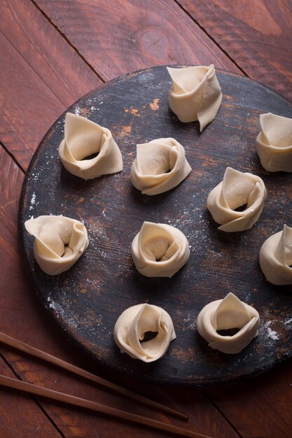 Wonton cru, prato chinês feito de massa e recheios. Fundo de madeira escuro