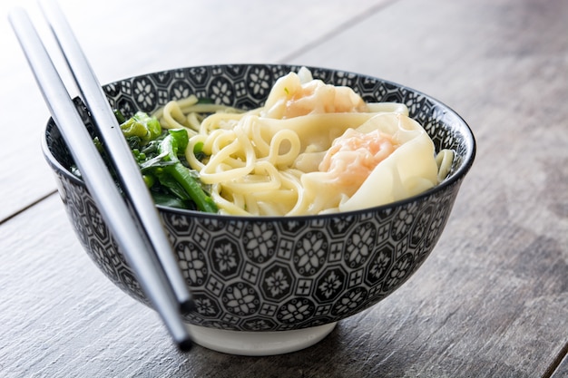 Wontonsuppe in einer Schüssel auf Holztisch