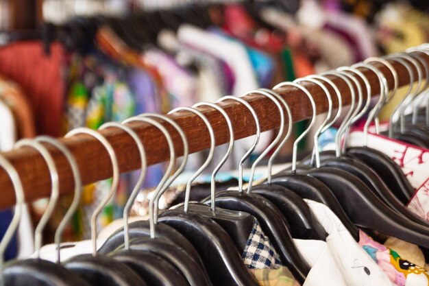 Foto wooden clothes racks with hangers and with colorful clothes on a blurred background inside shop