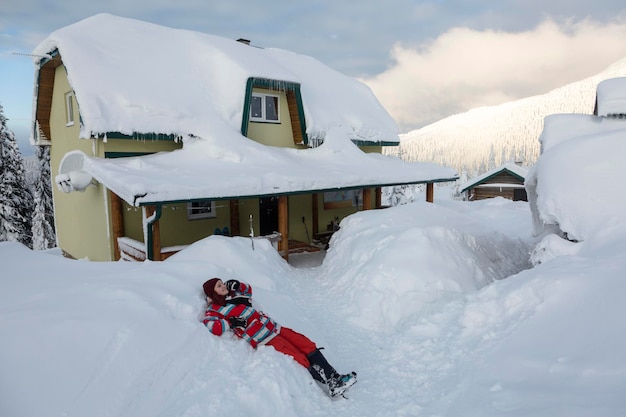 Wooman gosta da natureza perto de uma casa alpina com neve fofa branca nas montanhas de inverno