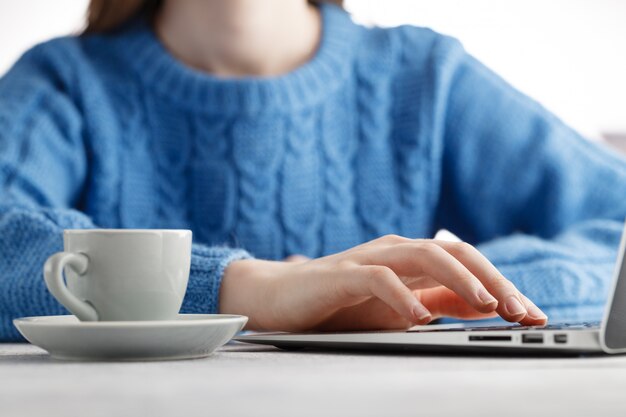 Woorking im Büro mit Laptop und Kaffee trinken