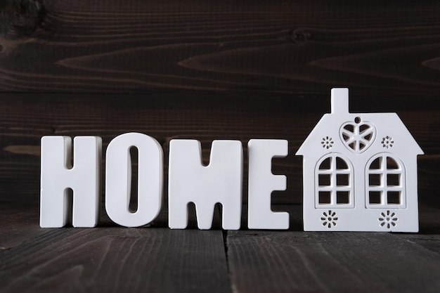 Word Home aus weißen Betonbuchstaben auf dem Holzhintergrund