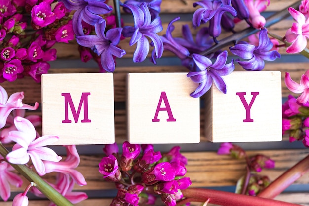 Foto word may letra del alfabeto en bloques de madera con flores de primavera frescas y coloridas