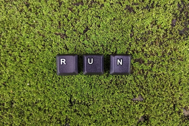 Word RUN hecho de letras de plástico negras sobre un fondo de musgo verde