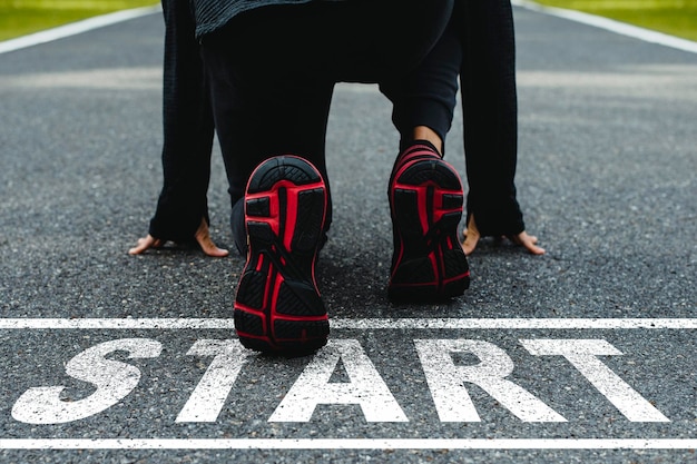 Word START escrito en la carretera asfaltada y el atleta corredor preparándose para comenzar a correr en la carretera Concepto de desafío o carrera y cambio