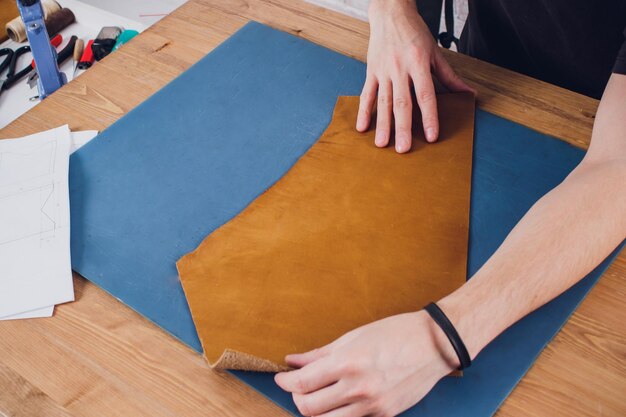 Working day in studio Man leather worker drawing sketch of purse with leather wallets and tools for sewing