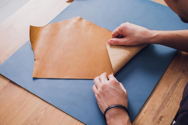 Working day in studio Man leather worker drawing sketch of purse with leather wallets and tools for sewing